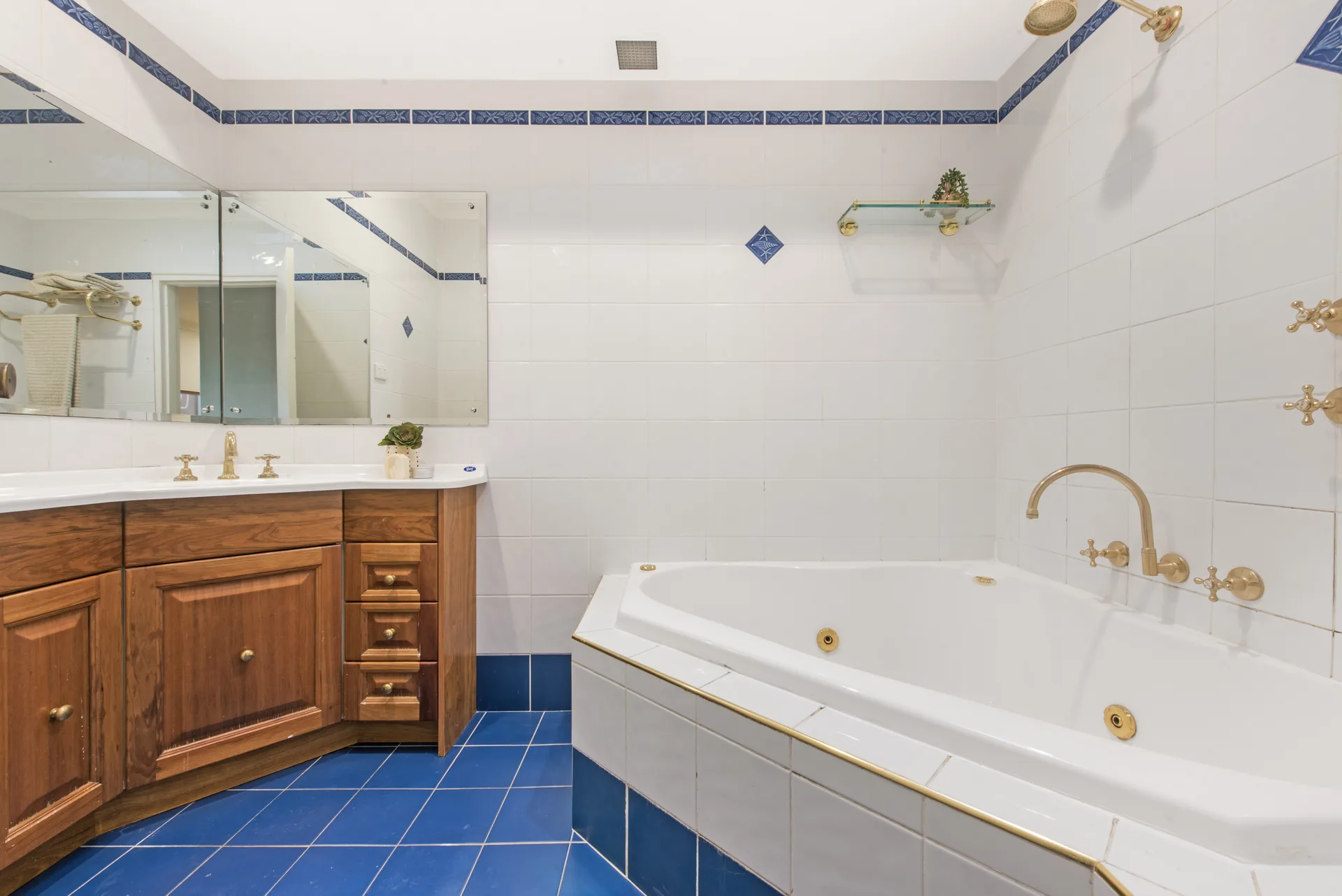 The same Drummoyne bathroom before the renovation, with cobalt floor tiles and a corner spa bath